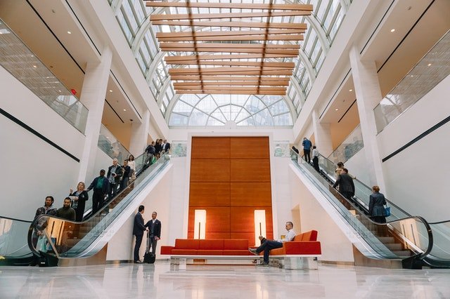 dva eskalátory plné ľudí v administratívnej budove sídla spoločnosti